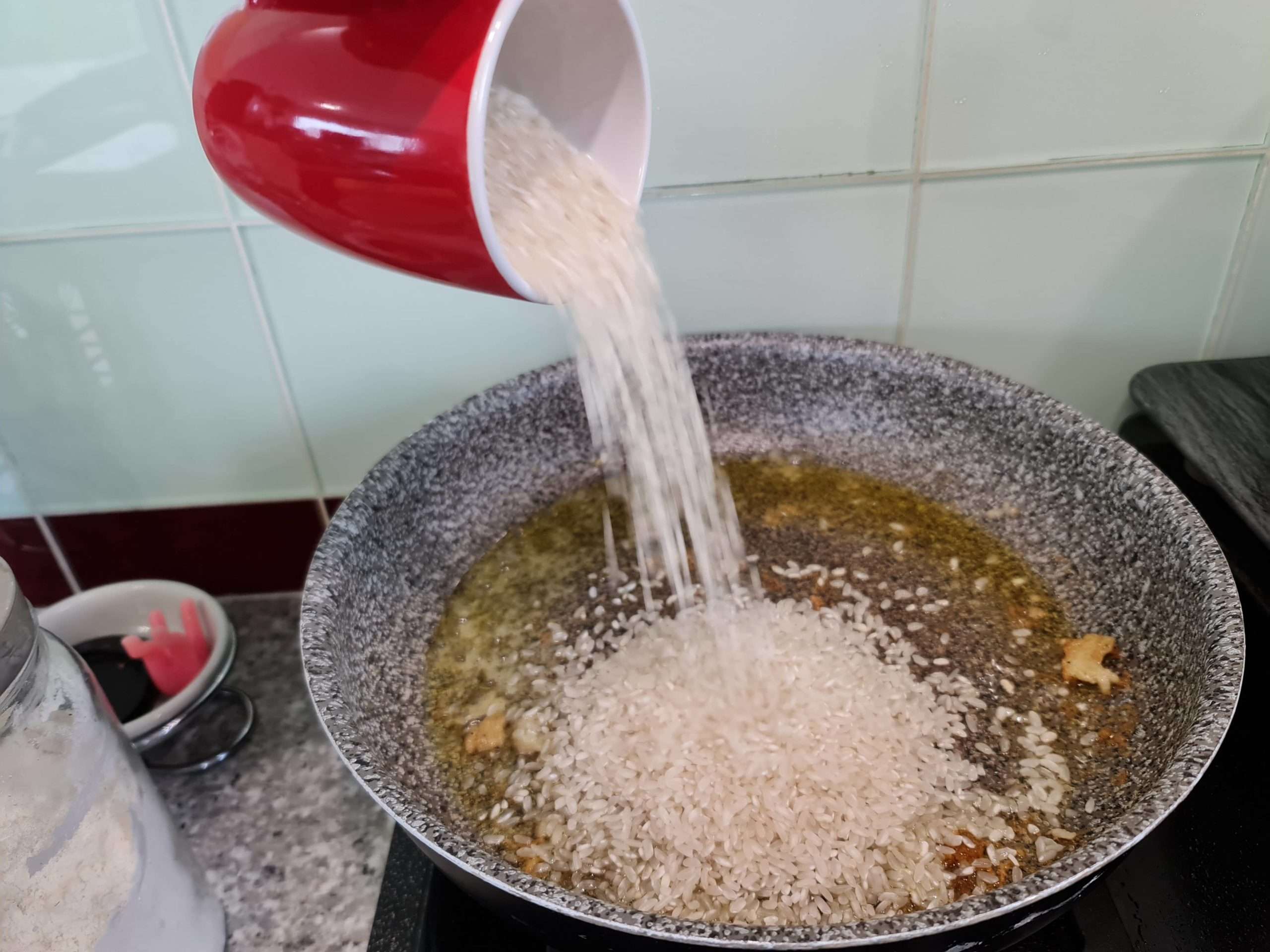Ajout du riz dans l'huile avec les morceaux de morue