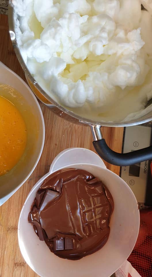 un plat avec des jaunes d'oeufs, une casserole avec des blancs en neige et un bol avec du chocolat fondu