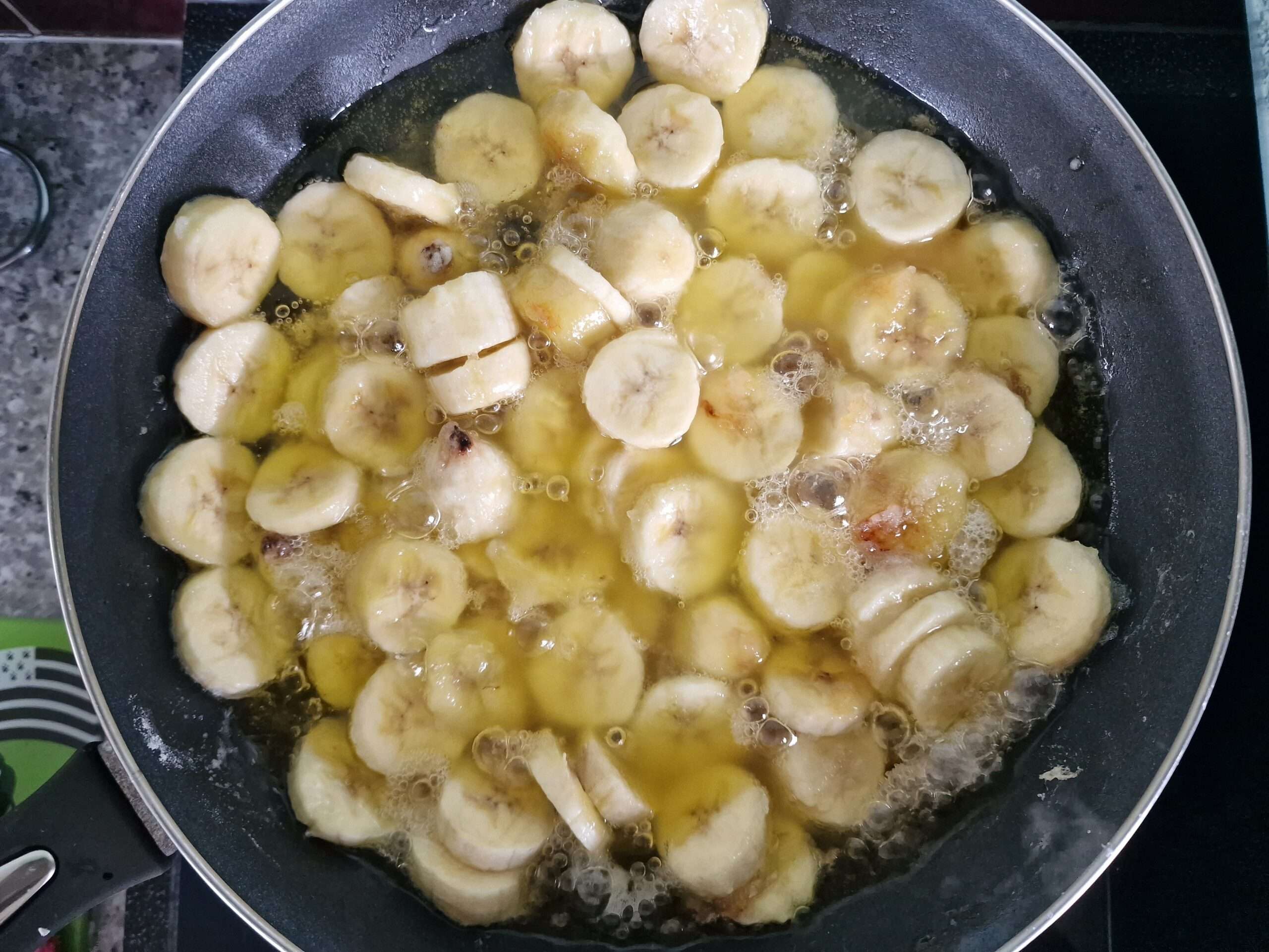 Bananes en morceaux dans une poêle avec du beurre et du sucre pour un délicieux cake à la banane.