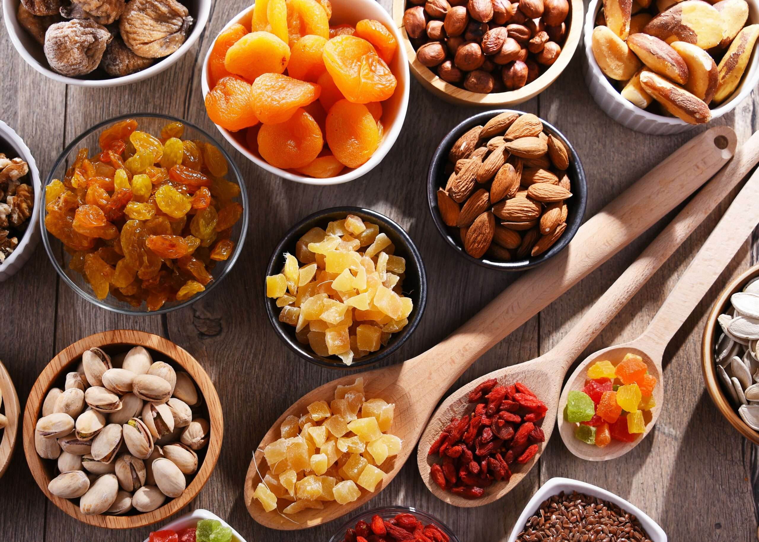 Une photo de différents types de fruits secs, tels que des amandes, des noix de cajou, des noix et des dattes, disposés sur une assiette.