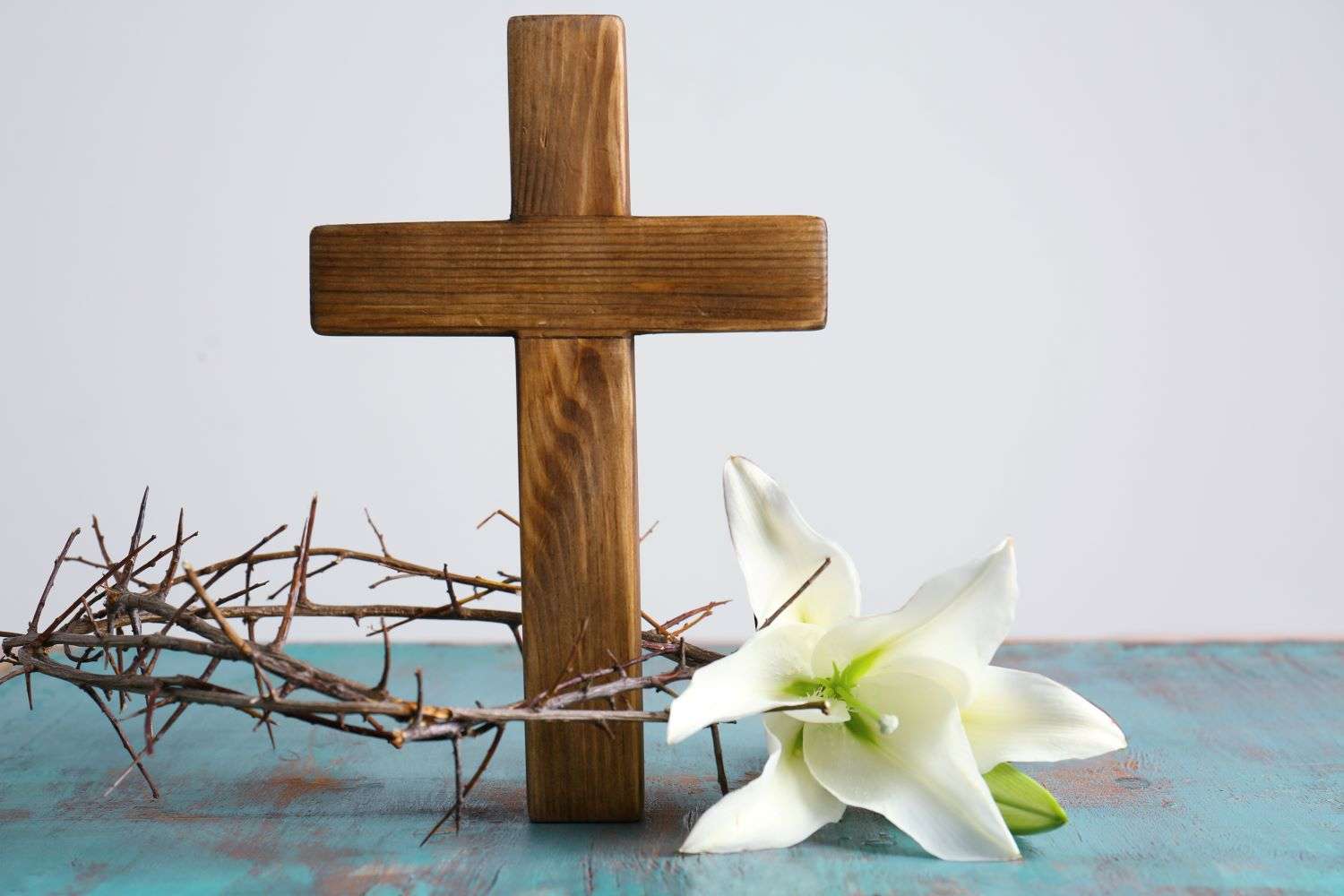 Une image d'une croix en bois avec des fleurs blanches disposées devant elle en hommage au Vendredi Saint.
