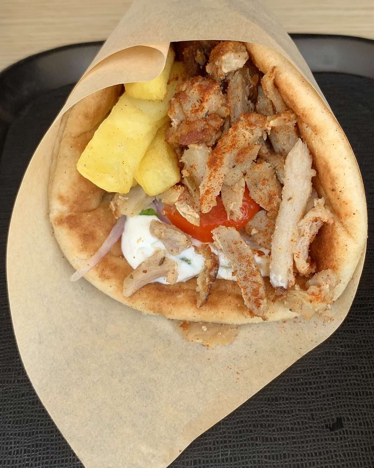 Pita gyros grec complet : viande, tzatziki, tomate, oignon et frites roulés dans le pain pita