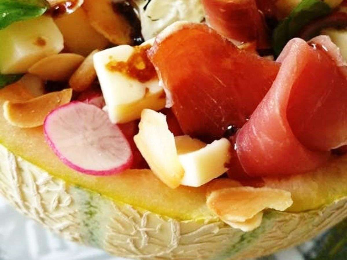 Gros plan sur la salade melon-pastèque à la feta : dés de feta, jambon cru, radis et amandes effilées