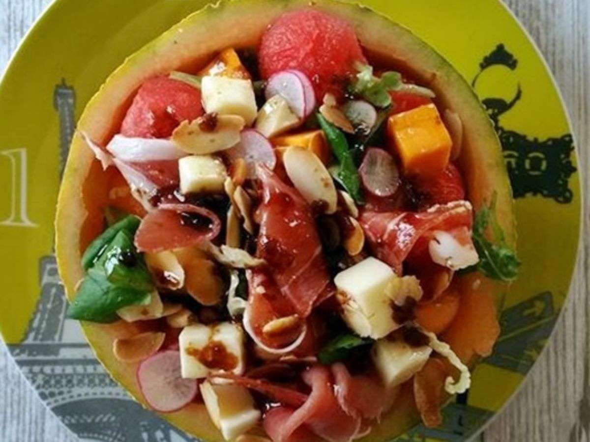 Salade melon-pastèque à la feta servie dans une coque de melon, avec jambon cru, radis et amandes grillées