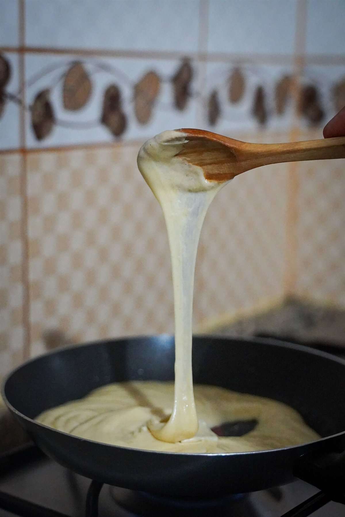 Sauce béchamel grecque aspri saltsa épaisse et crémeuse sur une cuillère en bois
