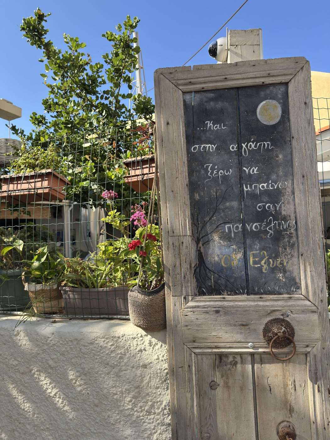 Ardoise peinte à la main sur une vieille porte en bois à l'entrée d'un lieu en Crète, avec un vers du poète grec Odysséas Elytis écrit à la craie