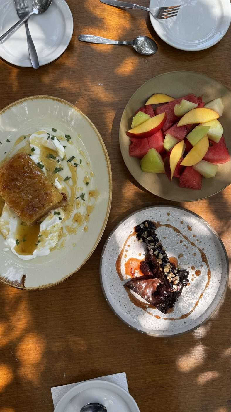 Desserts offerts en fin de repas dans une taverne crétoise : gâteau au miel et yaourt, assiette de fruits frais et pâtisserie au chocolat