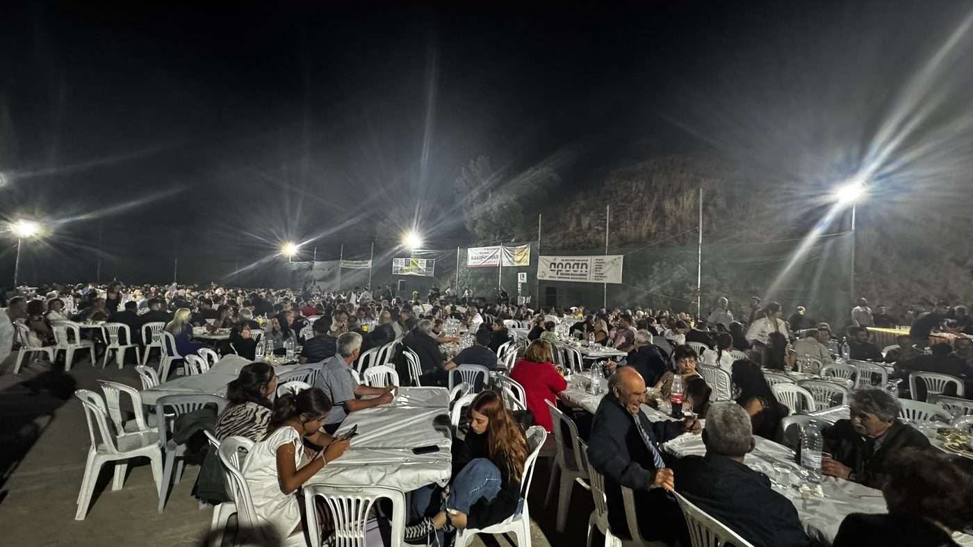 Grand repas de village la nuit lors d'un panigyri : des dizaines de tables blanches dressées en plein air au pied de la montagne