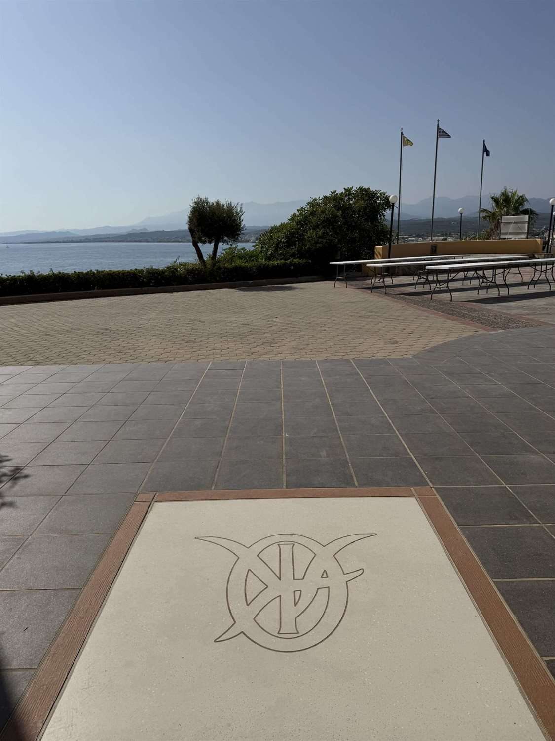 Longues tables blanches dressées sur l'esplanade de l'Académie orthodoxe de Crète à Kolymvari, face à la mer, avant un grand repas partagé