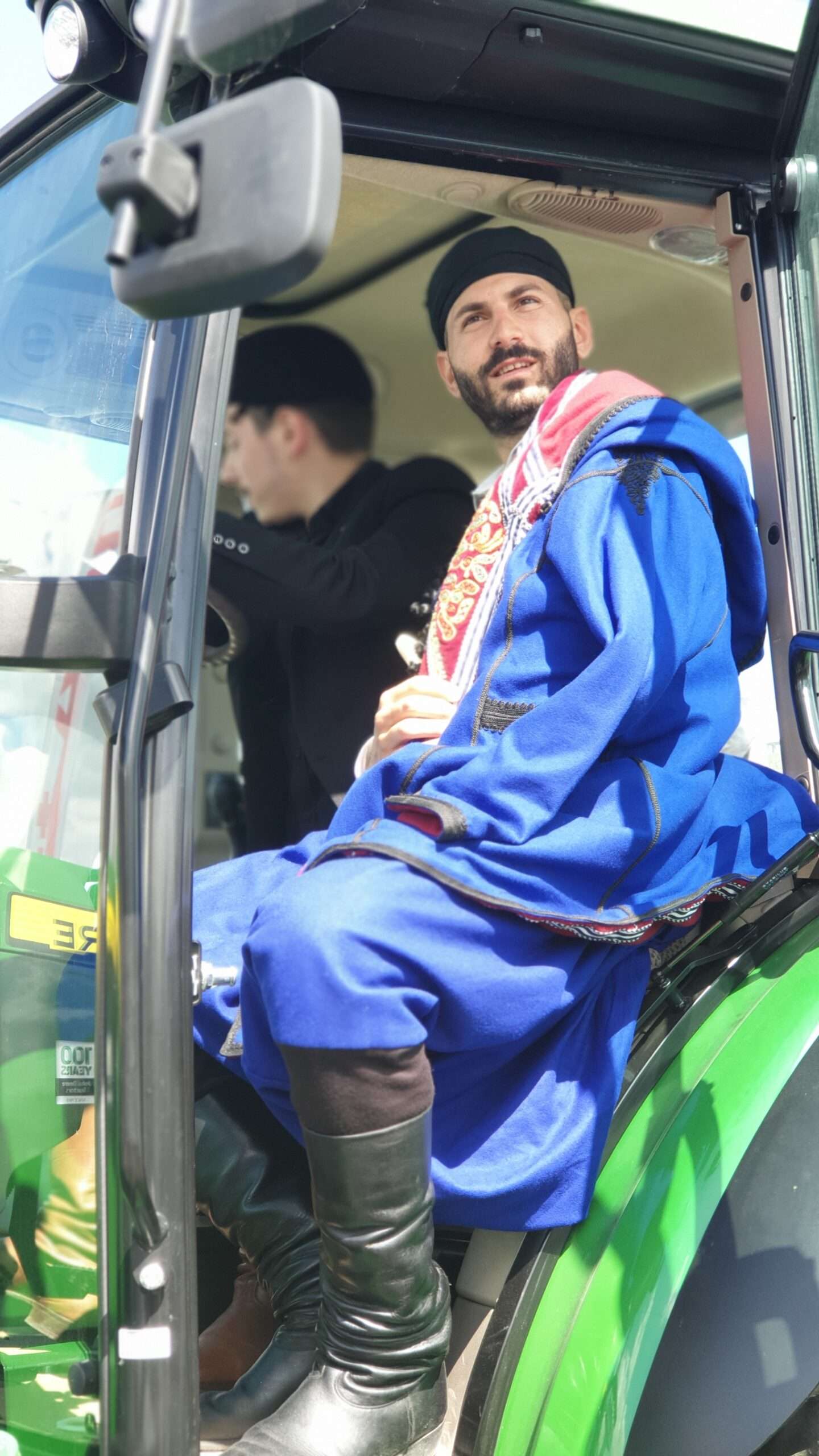 Dix ans de ponts entre la Normandie et la Crète 17 Un danseur crétois en costume au volant d'un tracteur, festival de la viande d'Évron 2019