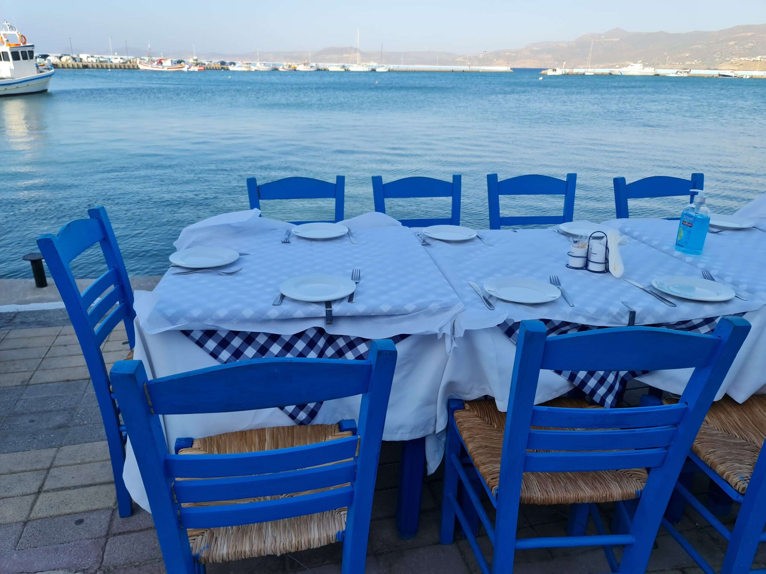 Ce que Socrate dirait de l'intelligence artificielle 20 Une table de taverne dressée au bord de la mer, chaises bleues, en Crète