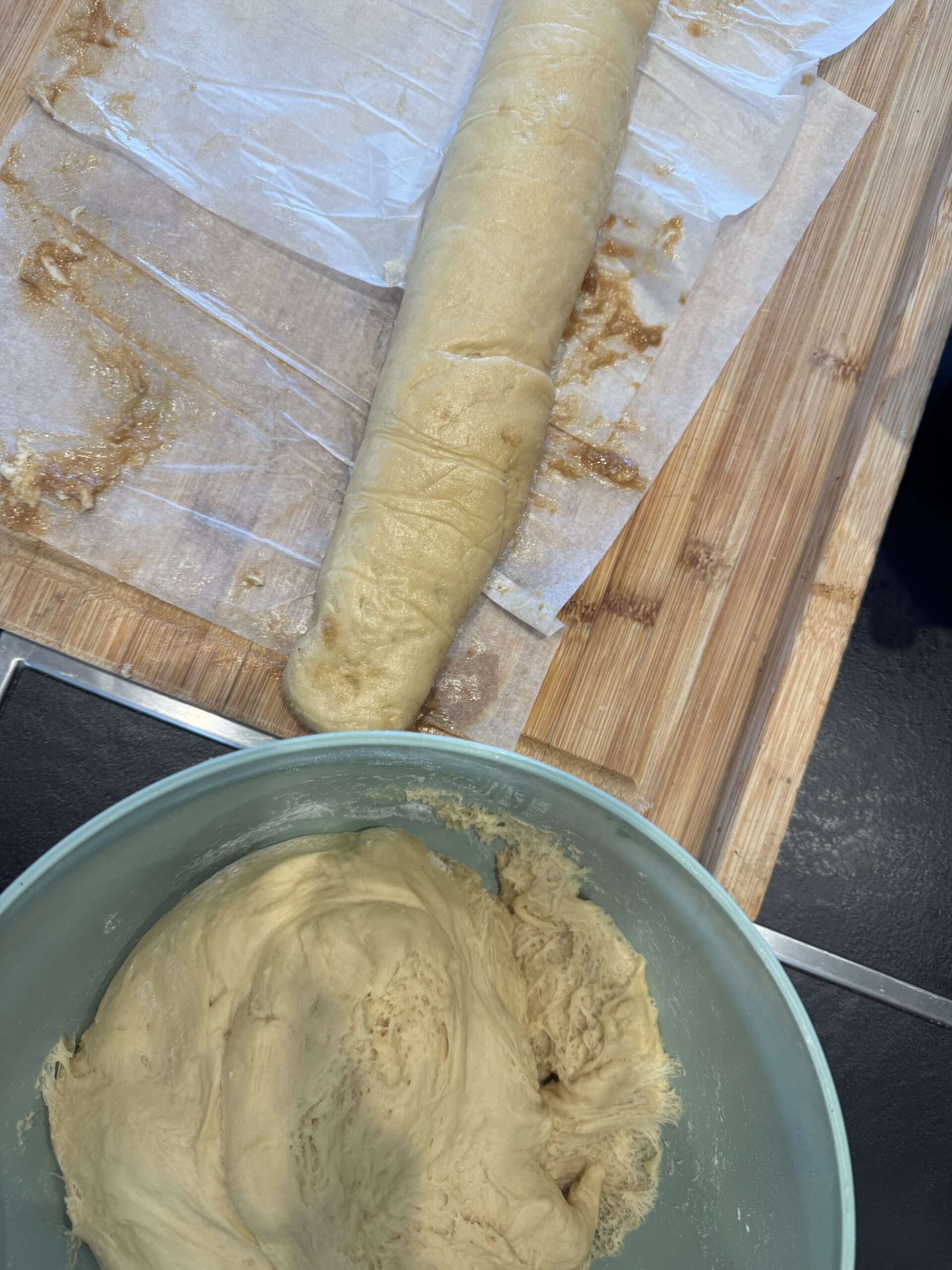 La pâte levée et le rouleau garni de tahini Pâte à brioche levée dans un saladier et rouleau garni de tahini sur le plan de travail