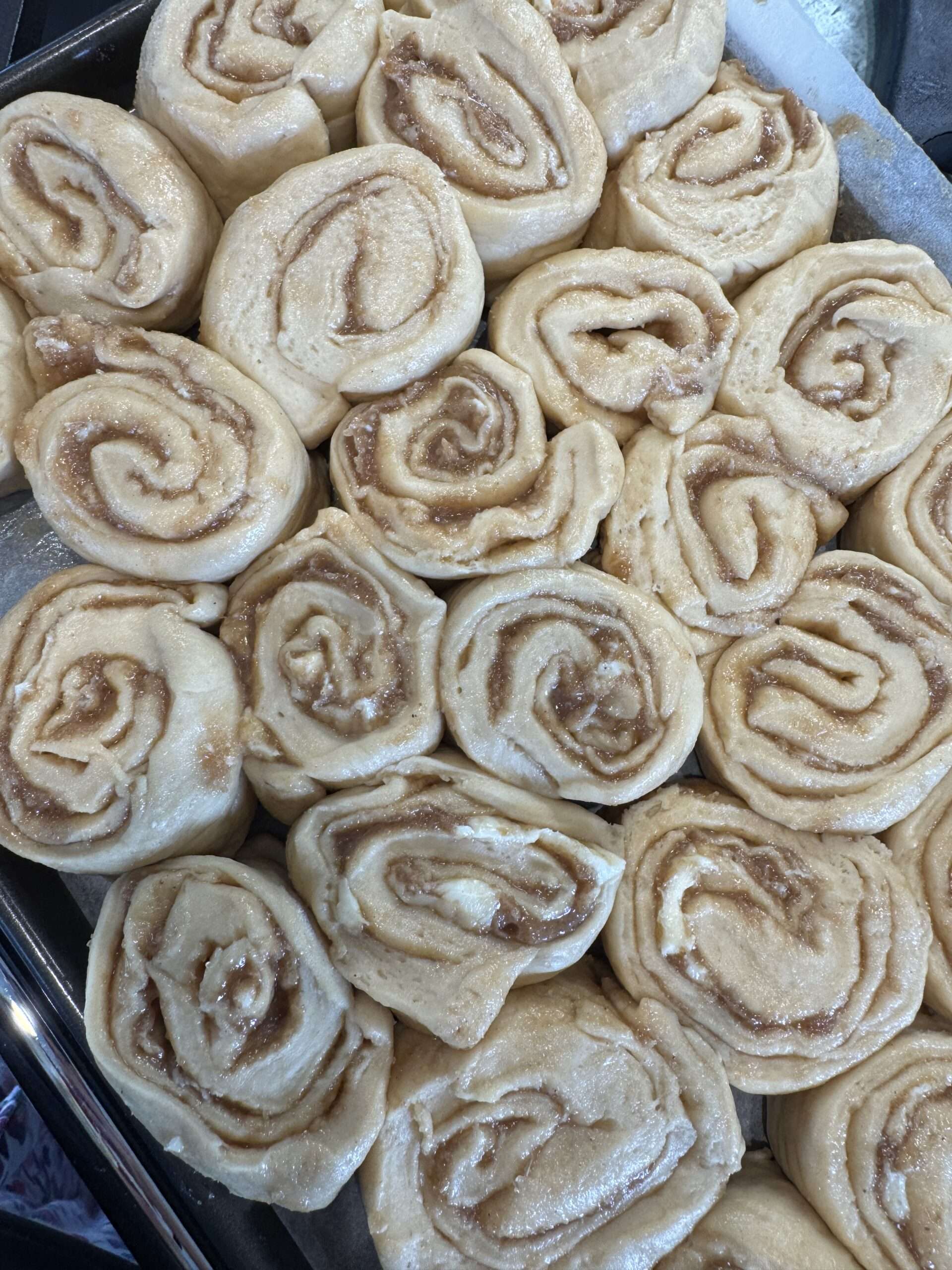 Dans la plaque, avant la deuxième levée Cinnamon rolls grecs au tahini serrés dans la plaque, avant la deuxième levée
