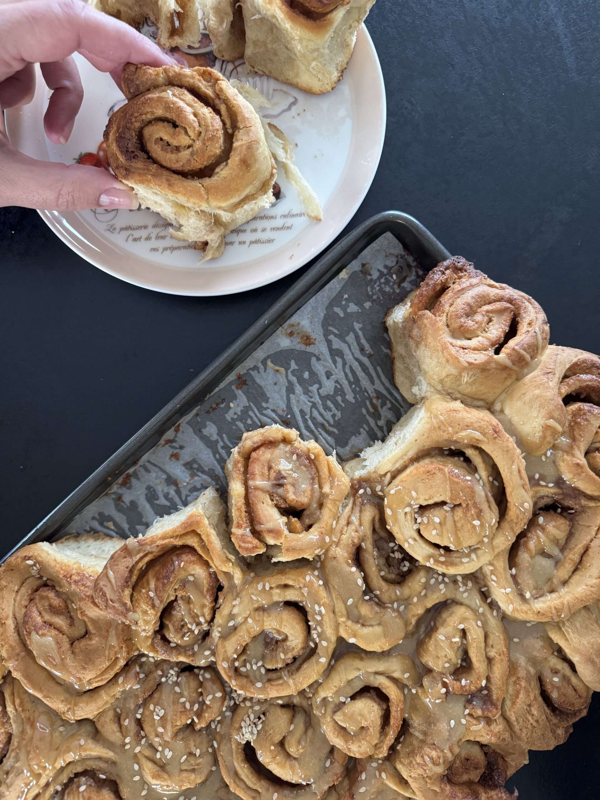 Un roll dans la main, encore tiède Un cinnamon roll grec au tahini et miel de thym tenu à la main
