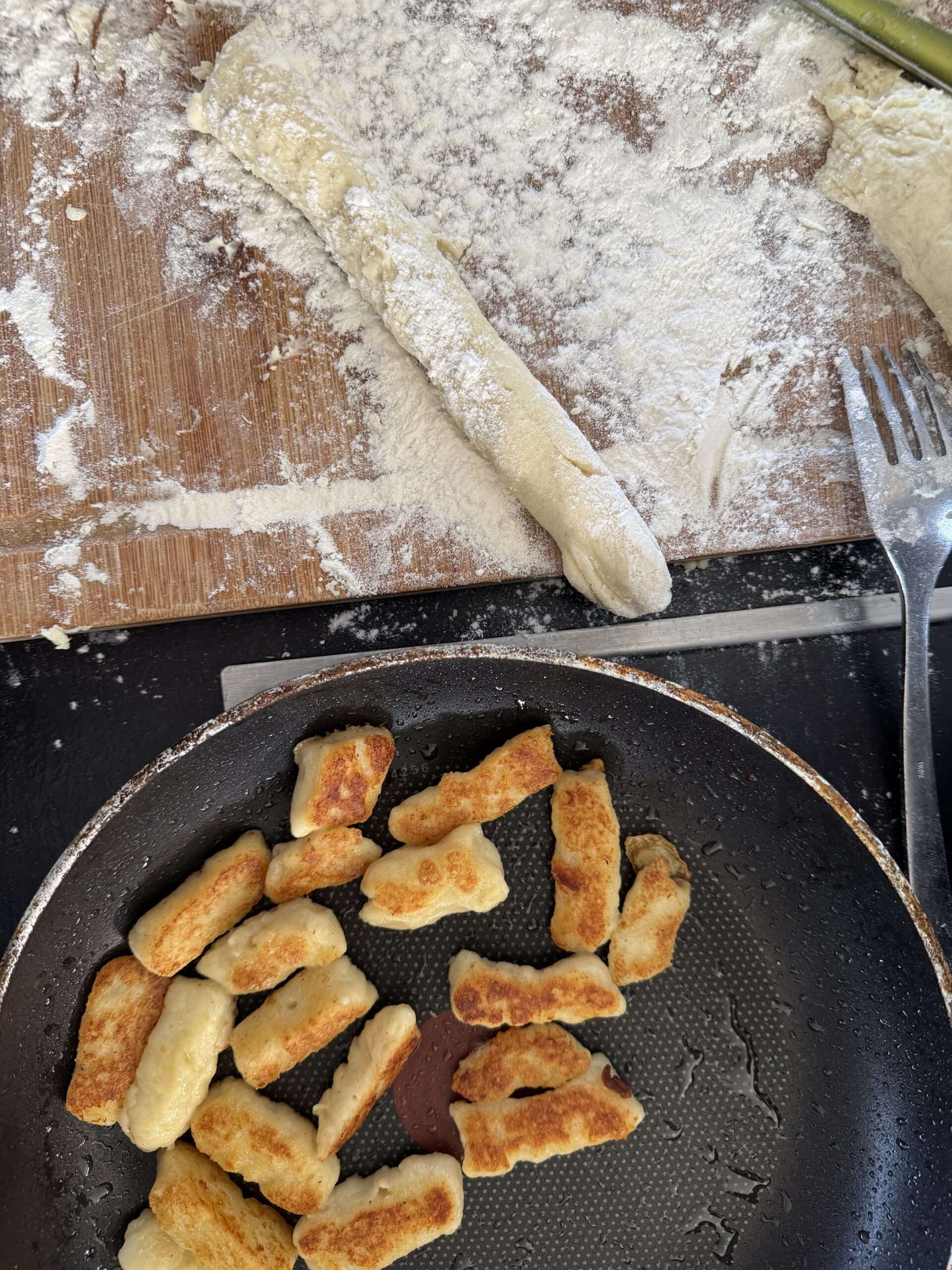 Gnocchis au manouri dorés dans la poêle, à côté des boudins de pâte farinés sur la planche