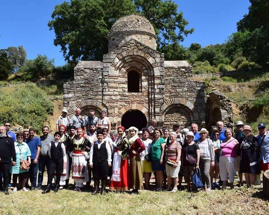Dix ans de ponts entre la Normandie et la Crète 2 Un groupe de l'association De la Normandie à la Crète, en Crète, devant une chapelle byzantine, avec des danseurs en costume crétois