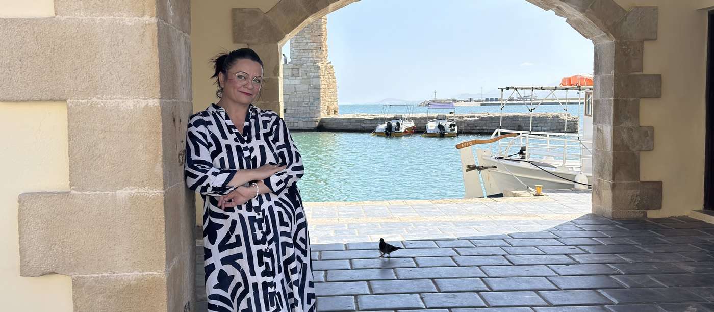 Maria Kassotaki sous une arche de pierre du port venitien de Rethymnon