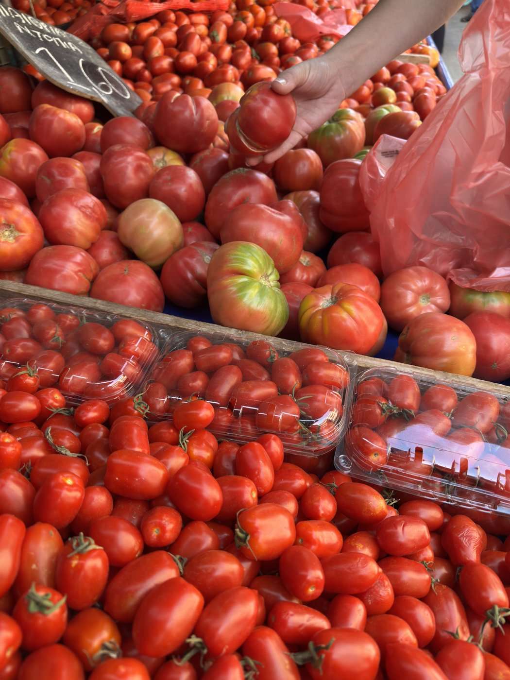Des tomates au marché en Crète, une main choisit les plus mûres